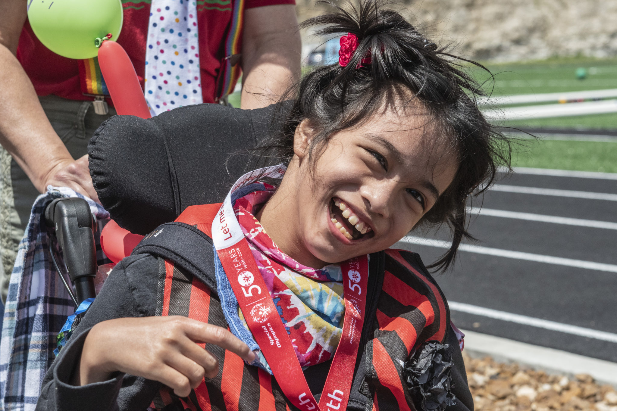 An athlete in a wheelchair wears a medal and smiles at the camera