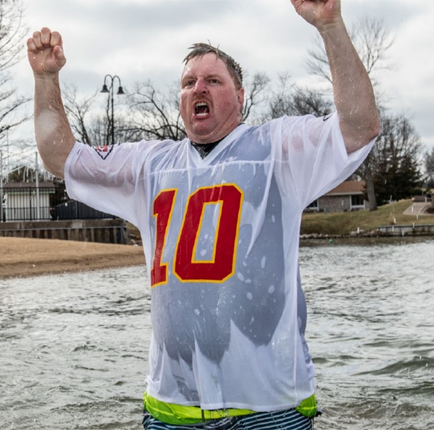 A Polar Plunger in a Chiefs jersey, soaked from head to toe, screams with their hands in the air