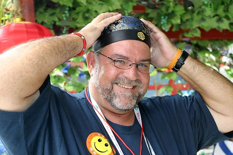 Gary Brimer wears a smiley face sticker and a bandana while smiling at the camera