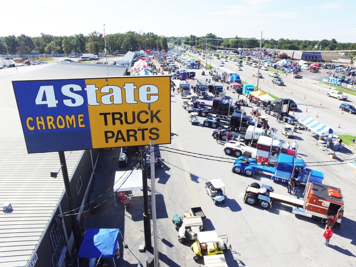 An aerial photo of dozens of semi trucks participating in a truck show with a 4 State Trucks sign in the foreground