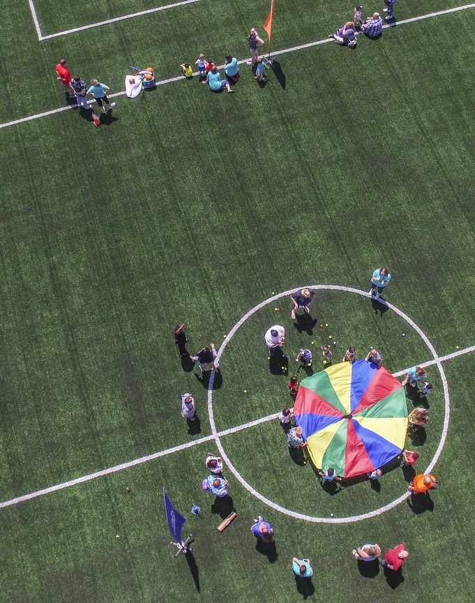 An aerial photo shows a group of Young Athletes and volunteers playing on the turf field at the Training for Life Campus