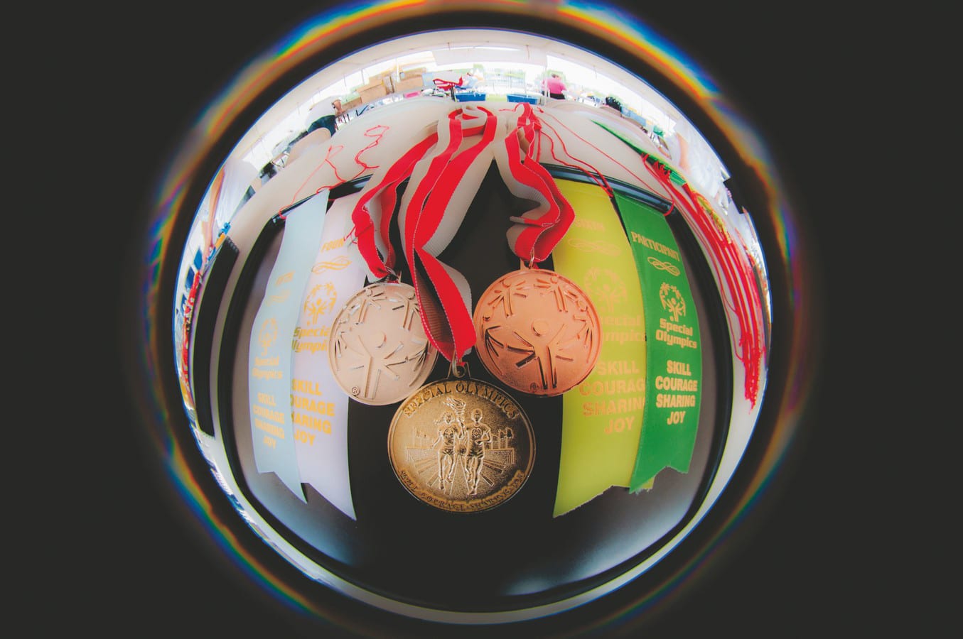 white, yellow, and green ribbons lay on a table with a silver, gold, and bronze medal