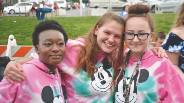 Three athletes in matching tie-dye hoodies pose for a photo with smiles on their faces