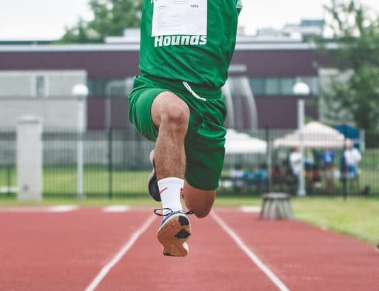 An athlete from Maryville has their arms outstretched as they fly though the air during a long jump competition