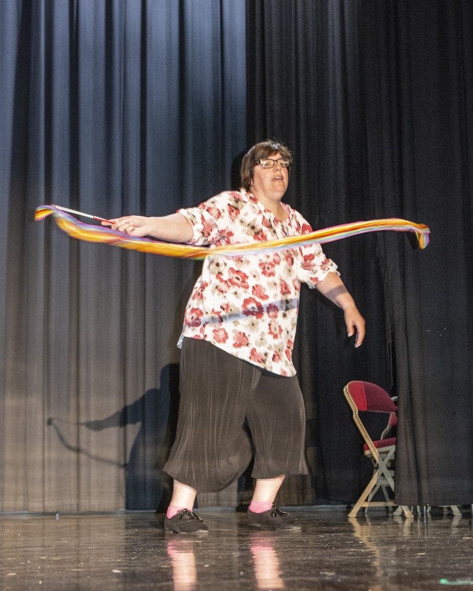 An athlete performs on a stage twirling with a dancing ribbon during a talent show
