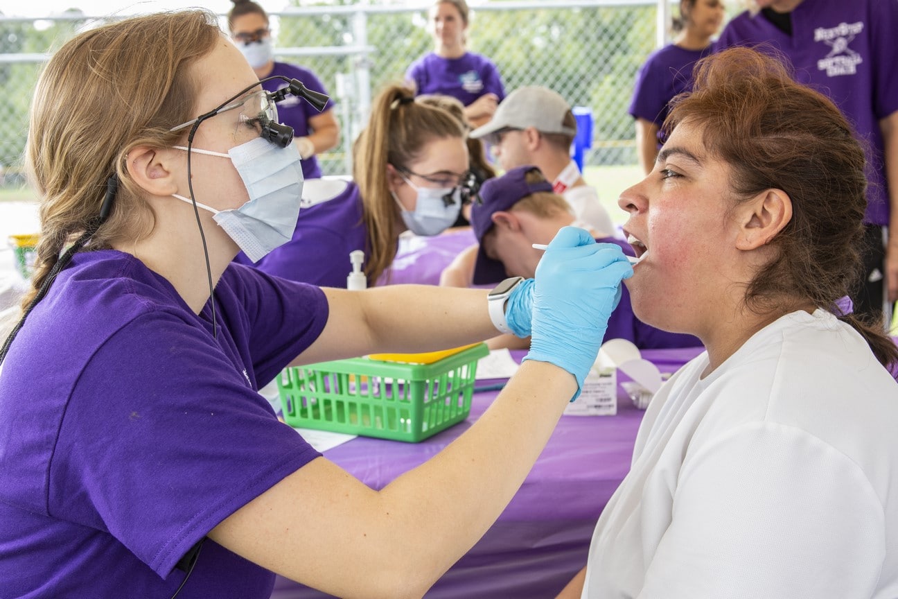 A health professional inspects the mouth of an athlete