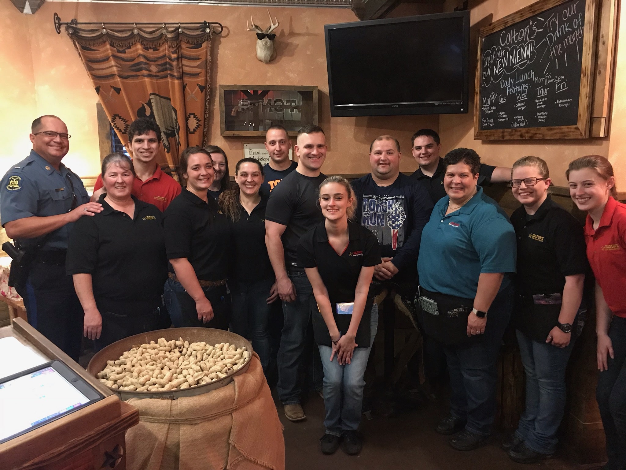 A group of law enforcement officers and servers pose for a photo in a restaurant