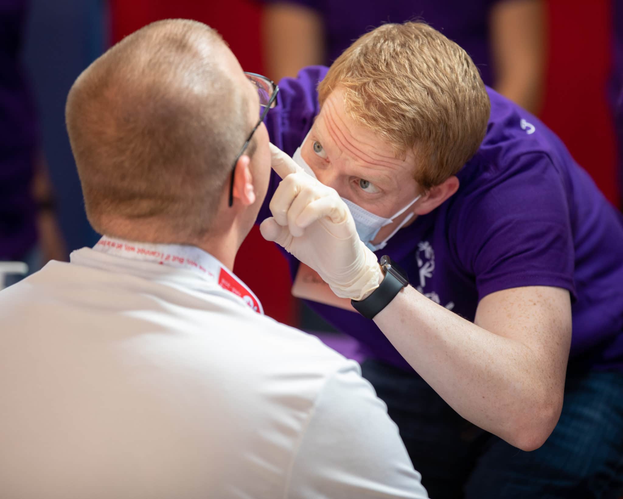 A dental volunteer bends over to look inside the mouth of an athlete