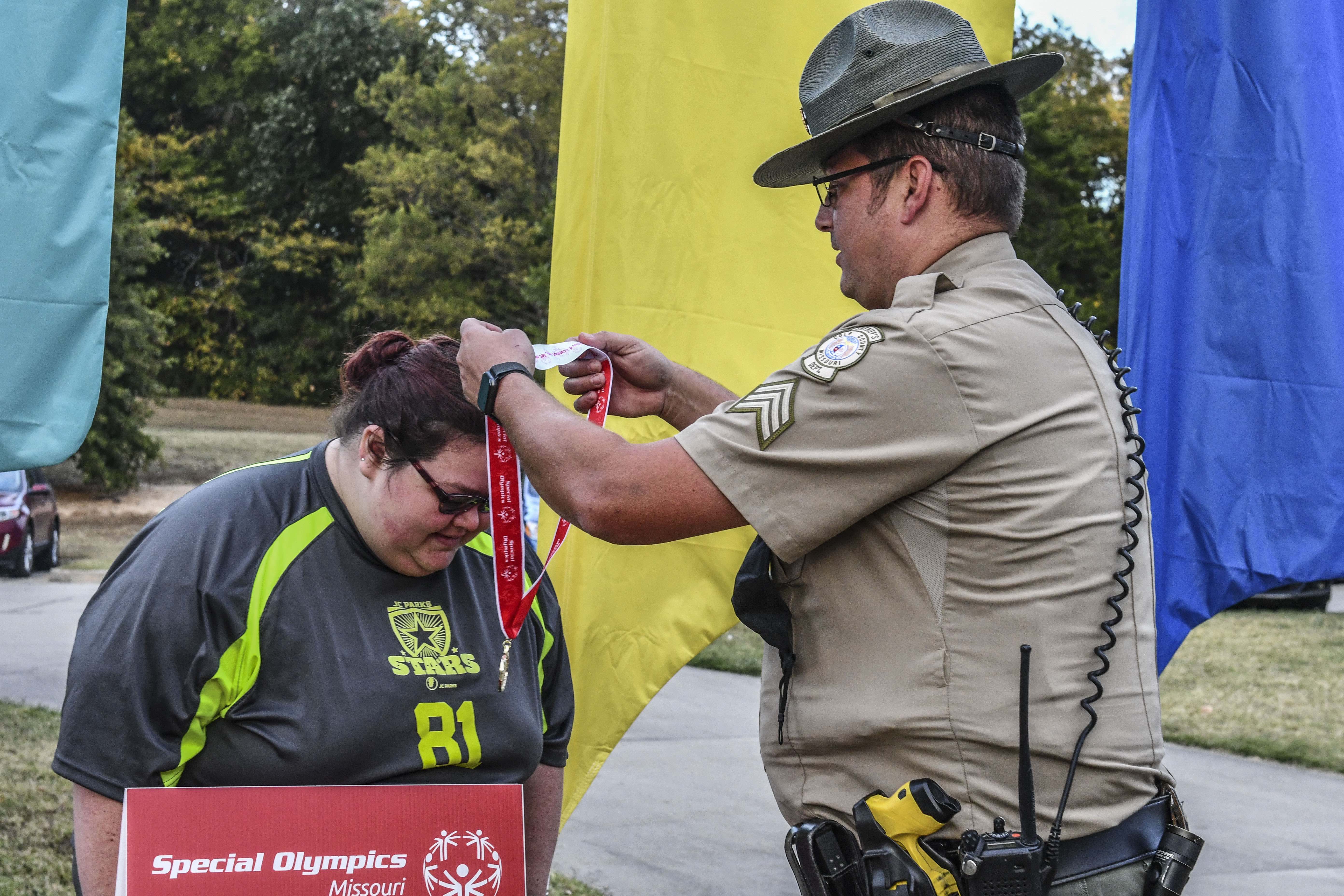 A law enforcement member hands out a medal to a Special Olympics Missouri athlete during the 2022 State Outdoor Games in Jefferson City, Mo.