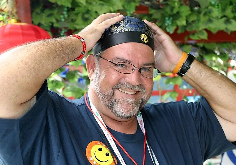 Gary Brimer wears a smiley face sticker and a bandana while smiling at the camera