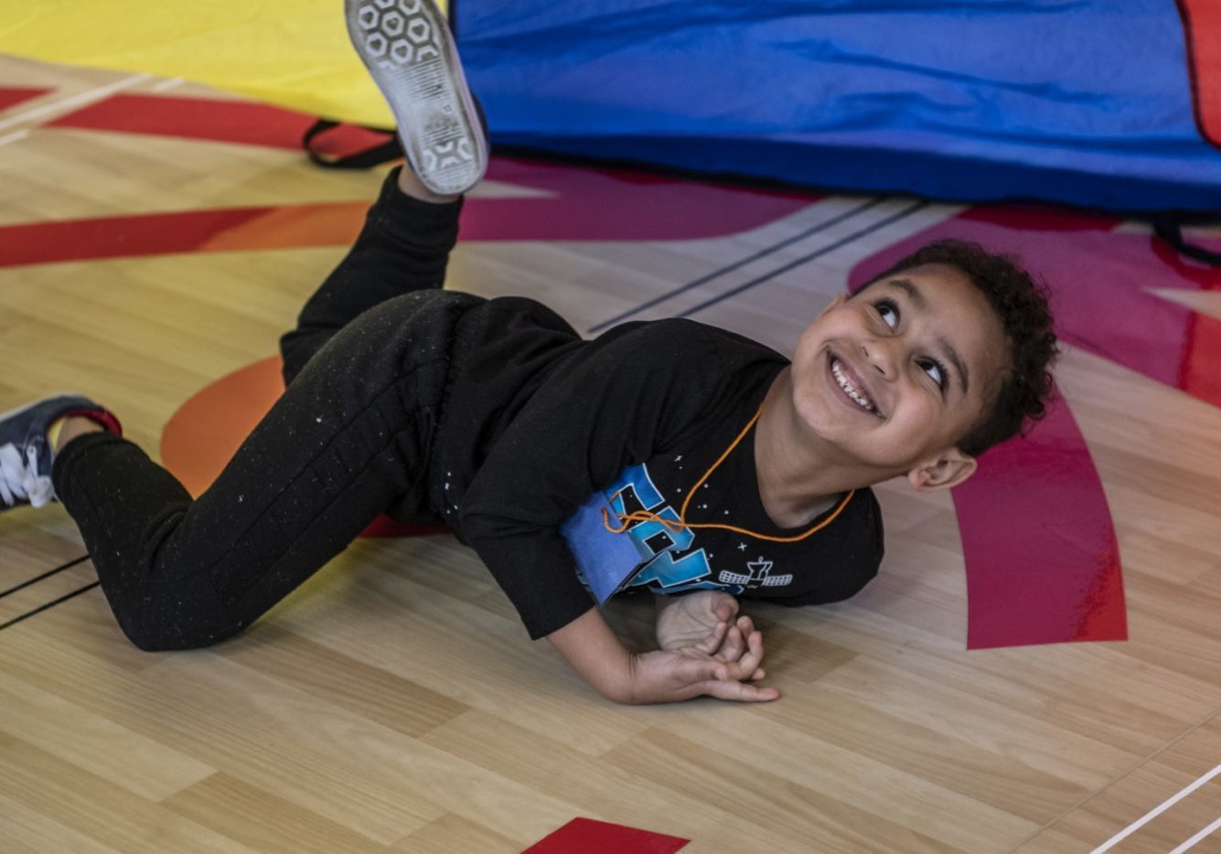 Young athlete laying on belly under a parachute and looking up while smiling