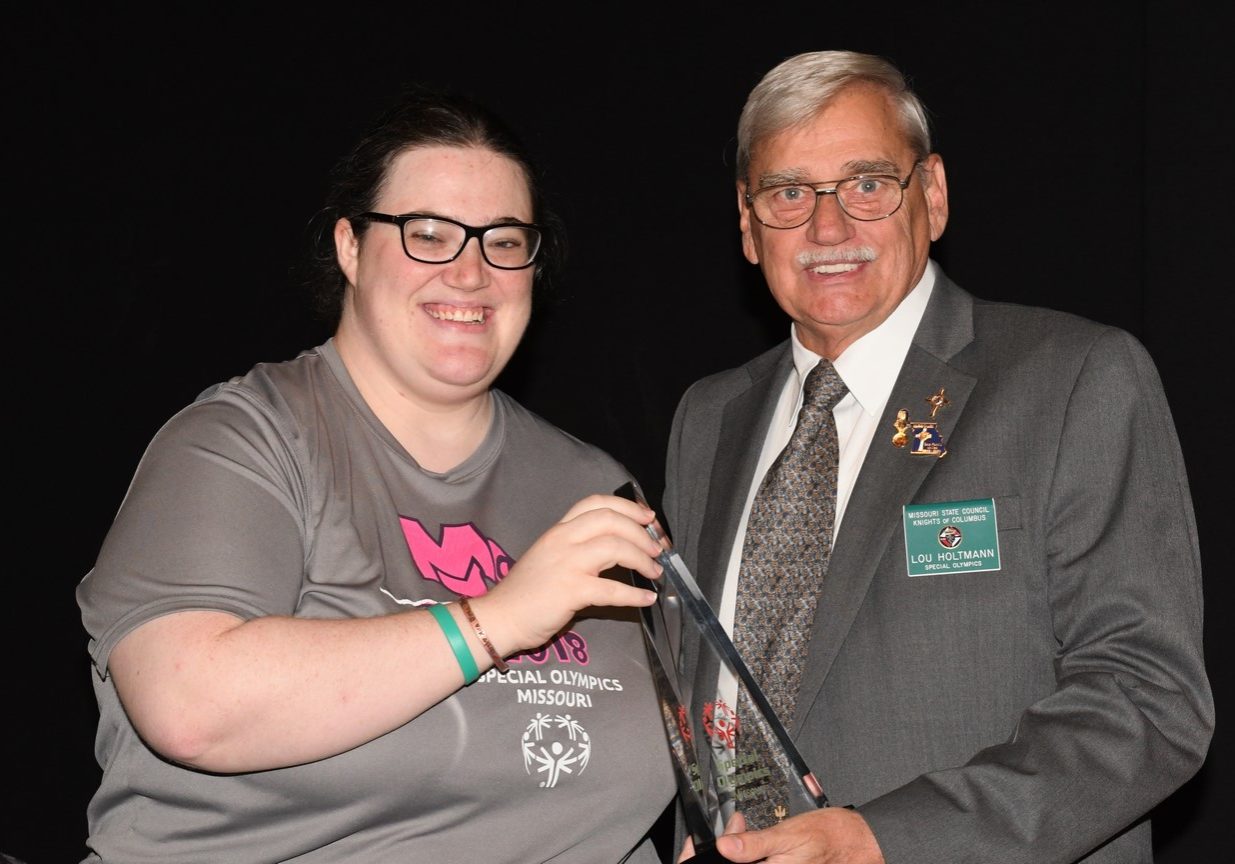 Athlete poses with volunteer holding an award